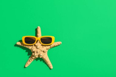 Yeşil arka planda şık güneş gözlüklü denizyıldızı
