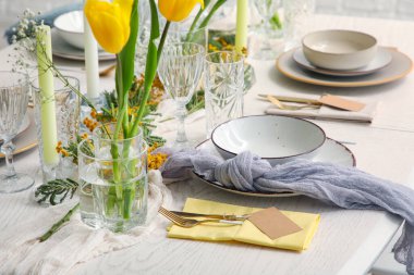 Restoranda güzel çiçekli ve altın çatal bıçaklı şık bir masa, yakın plan.