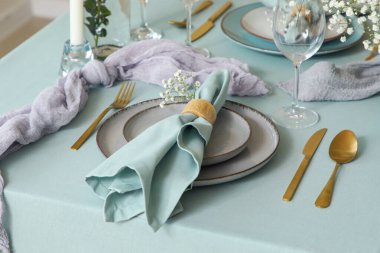 Güzel çiçekli, altın çatal bıçaklı ve restoranda katlanmış peçeteli zarif bir masa.