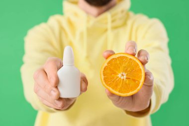 Yeşil arka planda damlaları ve turuncusu olan genç adam, yakın plan. Gıda Alerjisi Bilinci Ayı