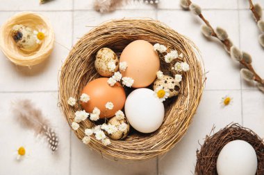 Paskalya yumurtaları, çiçekler, tüyler ve söğüt dalları beyaz fayanslı arka planda, yakın plan