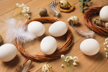 Tahta arka planda çelenkli, çiçekli ve tüylü Paskalya yumurtaları