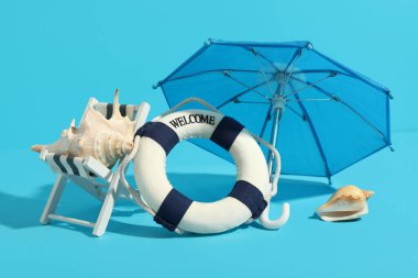 Renkli arka planda mini yaşam şamandırası, şezlong, şemsiye ve deniz kabukları ile yaratıcı kompozisyon