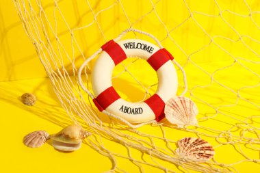 Mini can simidi, balık ağı ve sarı arka planda deniz kabukları.