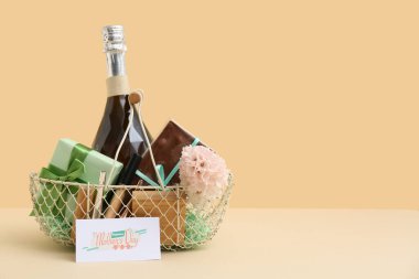 Bej arka planda Anneler Günü için şampanya şişesi, çikolata ve kozmetik ürünleri sepeti.