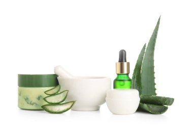Bir şişe kozmetik yağı ve beyaz arka planda aloe vera yapraklı krema kavanozları.