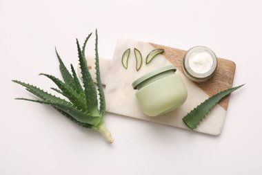 Beyaz arka planda aloe vera yapraklı kozmetik kremi kavanozları.