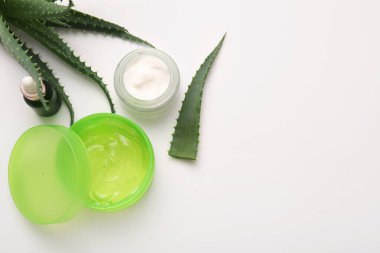 Beyaz arkaplanda aloe vera yaprakları olan farklı kozmetik ürünler