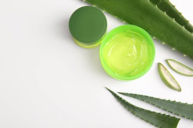 Beyaz arka planda aloe vera yapraklı kozmetik jel ve krem kavanozları.