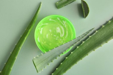 Yeşil arka planda aloe vera yapraklı kozmetik jel kavanozu