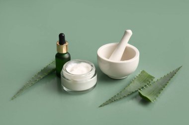 Yeşil zemin üzerinde aloe vera yaprakları olan farklı kozmetik ürünleri
