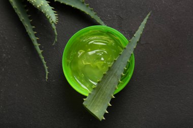 Siyah arka planda aloe vera yapraklı kozmetik jel kavanozu