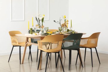 Odada ışık duvarının yanında bahar çiçekleri olan masa ayarı