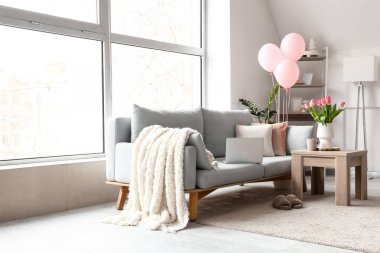Kadınlar Günü için dekore edilmiş oturma odasının içi kanepe, masa ve balonlarla dolu.