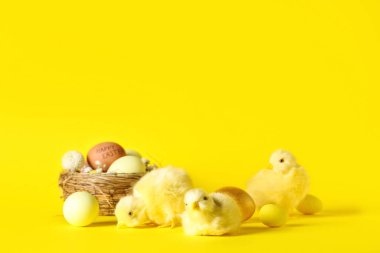 Paskalya yumurtalı yuva, güzel çiçekler ve sarı arka planda yavru tavuklar.