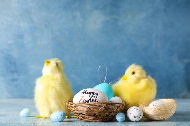 Mavi arka planda Paskalya yumurtaları ve yavru tavukları olan yuva.