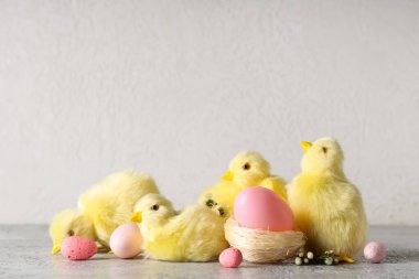 Pembe Paskalya yumurtaları, yavru tavuklar ve gri masada güzel çiçekler.