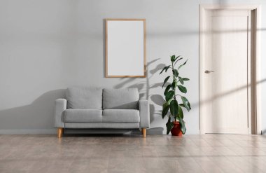 Oturma odasının içi gri kanepe, bitki ve boş çerçeve.