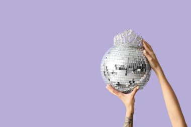 Disko topu ve leylak kaplamalı taç takan kadın eller. Balo konsepti