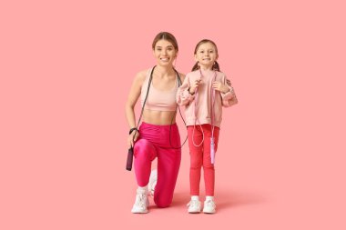 Sportif genç anne ve pembe arka planda spor aletleri olan sevimli küçük kızı. Anneler Günü kutlaması