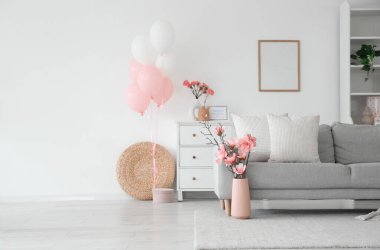 Anneler Günü için dekore edilmiş aydınlık oturma odasının içi kanepe, çiçekler ve balonlarla dolu.