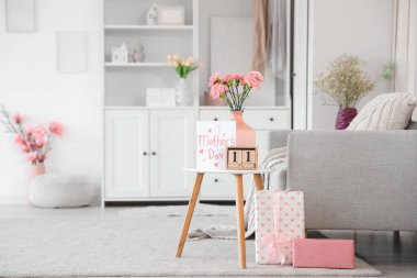 Anneler Günü için masa, kanepe ve çiçeklerle süslenmiş aydınlık oturma odasının içi.