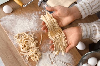 Makarna tutan genç bir kadın mutfak masasının yanında makineyle yapılmış.