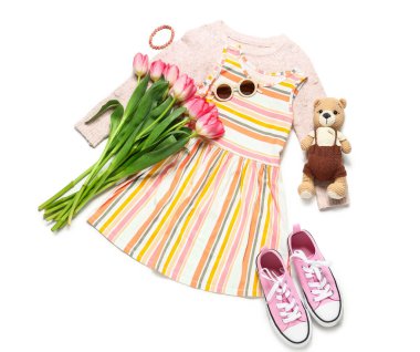 Ayı oyuncağı ve beyaz arka planda laleleri olan küçük bir kız.