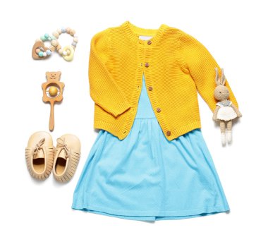 Beyaz arka planda oyuncakları olan küçük bir kız bahar kıyafeti.