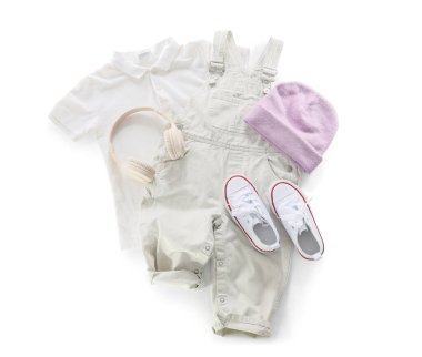 Beyaz arka planda şık çocuk kıyafetleri, ayakkabıları ve modern kulaklıkları.