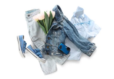 Şık çocuk kıyafetleri, ayakkabıları, fotoğraf makinesi ve beyaz arka planda lale çiçekleri olan kompozisyon