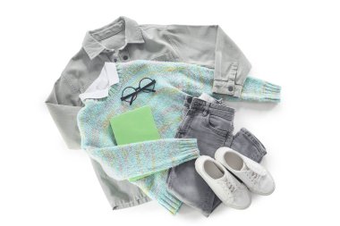 Şık çocuk kıyafetleri, ayakkabıları, gözlükleri ve beyaz arkaplan üzerine kitabı olan kompozisyon