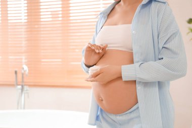 Banyoda bir kavanoz kremalı hamile kadın.