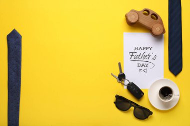 Mutlu Babalar Günü yazılı kart, erkek aksesuarlar, araba anahtarı ve sarı arka planda bir fincan kahve.