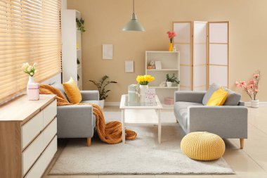 Anneler Günü için dekore edilmiş oturma odasının içinde kanepeler, masa ve raf üniteleri var.