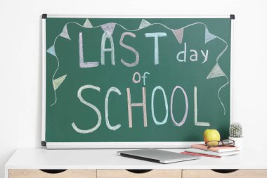 Not defterleri, elma ve metin içeren masa Işık duvarının yanındaki tahtada okulun son günü