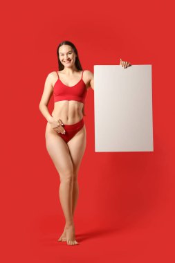 Kırmızı arka planda adet takvimi olan iç çamaşırlı genç bir kadın.