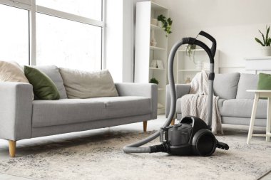 Elektrikli süpürge ve kanepelerle aydınlık oturma odasının içinde.