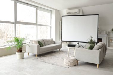 Boş projektör ekranlı, kanepeli ve masalı aydınlık oturma odasının içi