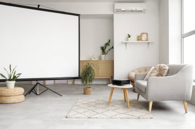 Boş projektör ekranlı, kanepeli ve masalı aydınlık oturma odasının içi.