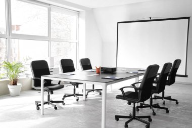 Boş projektör ekranı ve masası olan konferans salonunun içi