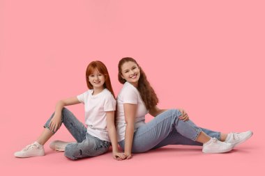 Tatlı kızı pembe arka planda oturan güzel genç bir kadın. Anneler Günü kutlaması