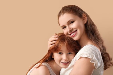 Güzel genç bir kadın kahverengi arka planda sevimli kızına sarılıyor. Anneler Günü kutlaması