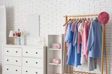 Açık renk soyunma odasının içinde askılık, çekmeceler ve katlanır ekran var.