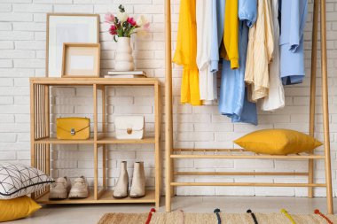 Giysi askılığı ve raf ünitesi olan hafif soyunma odasının içinde.