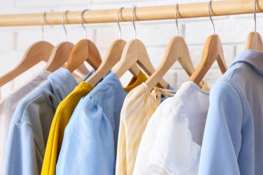 Beyaz tuğla duvarın yanında şık elbiseli ahşap askı, yakın plan.