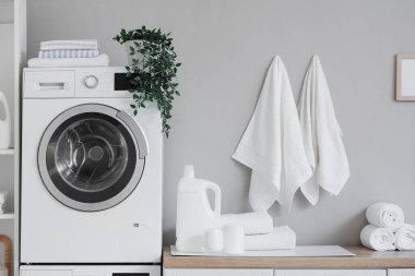 Çamaşır makinesi, havlu ve tezgahı olan hafif çamaşır odasının içi.