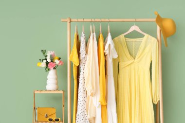 Renkli duvarın yanında şık kadın kıyafetleri, aksesuarlar ve çiçeklerle doldur.