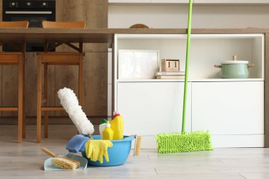 Mutfakta yerde temizlik malzemeleri olan plastik bir leğen.