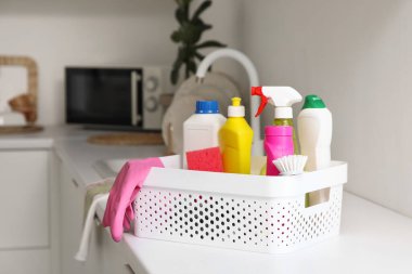 Mutfaktaki masada temizlik malzemeleri olan plastik sepet, yakın plan.